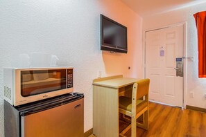 A compact kitchenette with a microwave, a small refrigerator, a wooden table, and a chair. - 2 Full Beds | Non-Smoking (Bakersfield)