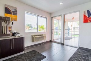 A reception area with a coffee machine, a vent, and a glass door leading outside. - 1 Queen Bed | Smoking (Bakersfield)