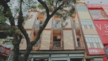 A multi-story building with balconies, a storefront at the ground level, and signage in a local language.