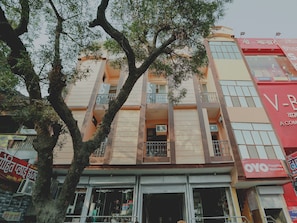 Un edificio de varios pisos con balcones, una tienda en la planta baja y señalización en idioma local.