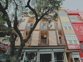 Un edificio de varios pisos con balcones, una tienda en la planta baja y señalización en idioma local.