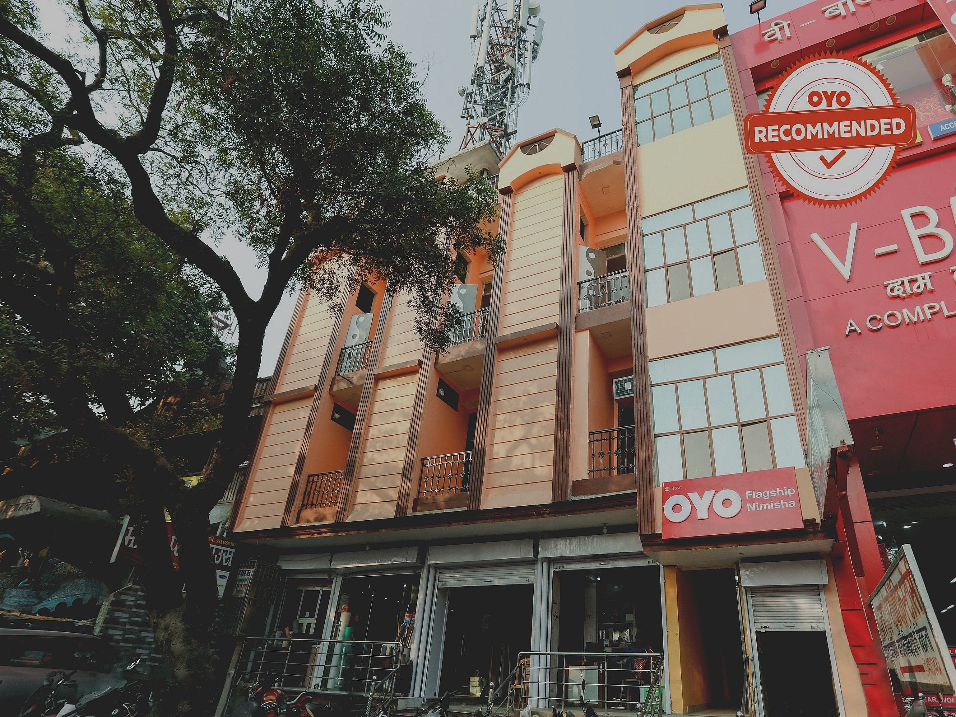 A multi-story building with balconies, a prominent 'OYO Recommended' sign, and a visible storefront with signage in a foreign language.