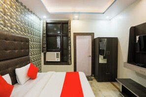 Una habitación de hotel con una cama, un armario, un televisor y aire acondicionado.