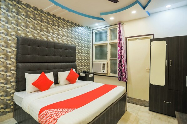 A bedroom with a bed, a wardrobe, a window with a curtain, and a patterned wall.
