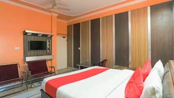 A hotel room with a bed, a desk, a chair, a television, and a wardrobe.
