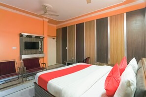 Una habitación de hotel con una cama, un escritorio, una silla, un televisor y un armario.