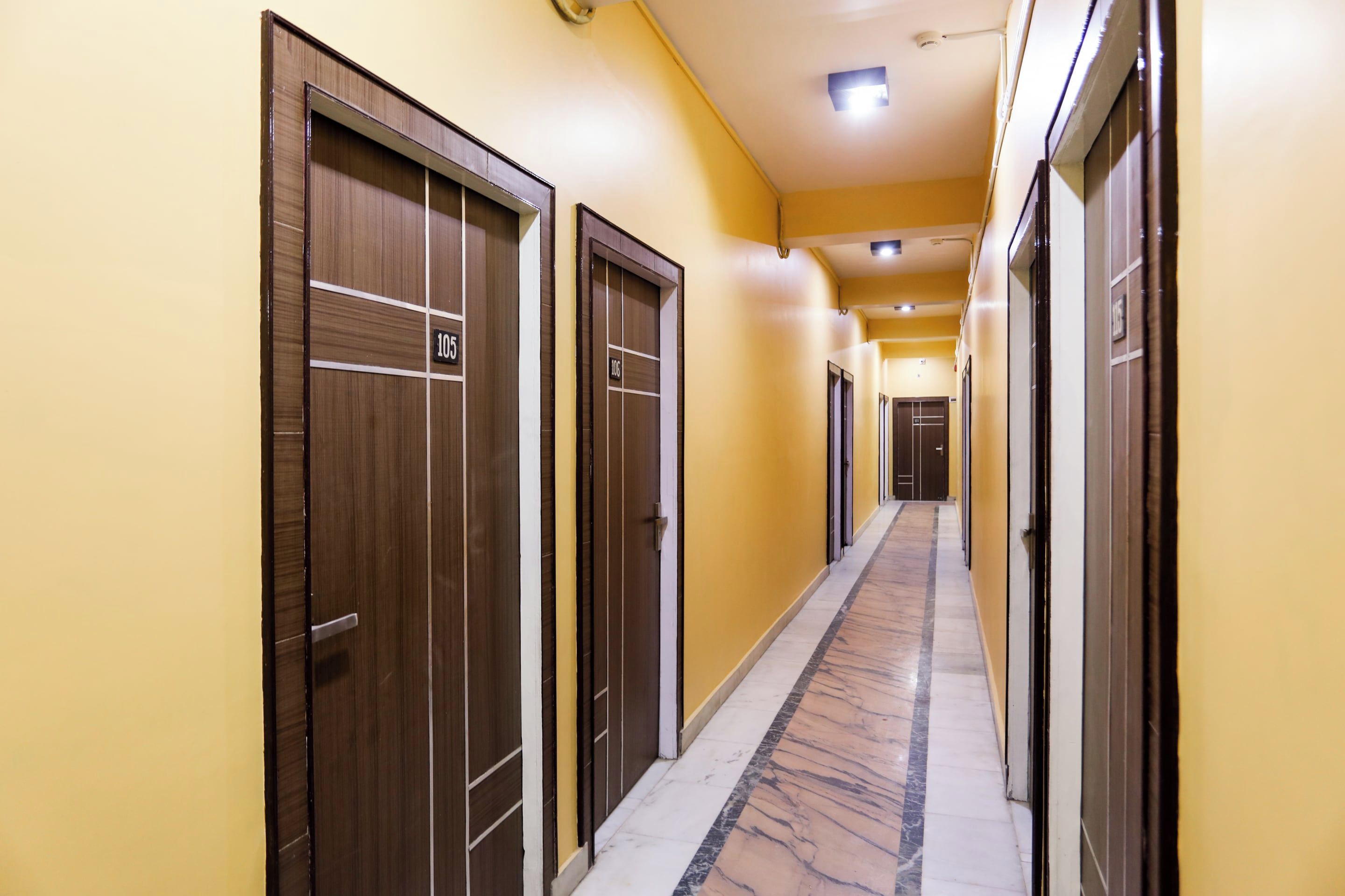 A hotel corridor with wooden doors numbered 105 and 106, leading to rooms.