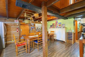 Un interior de madera con una mesa de comedor, sillas, una zona de cocina y una estantería para vinos.