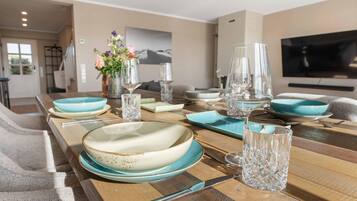 Un coin repas avec une table en bois mise pour quatre personnes, comprenant des assiettes, des verres et des couverts.