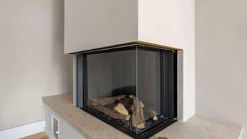 A corner fireplace with a glass enclosure, a stone base, and a visible fire.