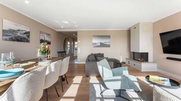 En moderne stue med spiseområde, sofaarrangement og fladskærms-tv.