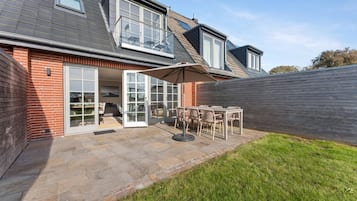 Il s’agit d’une propriété résidentielle dotée d’un patio, d’une porte-fenêtre coulissante et d’un espace extérieur couvert aménagé en coin salon.