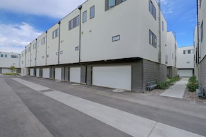 A modern multi-story residential building with a row of garage doors, a clear sky, and a paved driveway. - Leos Cozy Getaway near SLC Airport & Downtown (Salt Lake City)