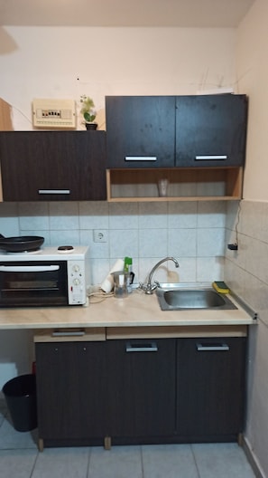 A compact kitchen with a microwave, sink, and cabinets. - Renovated Studio Heart City (Thessaloniki)