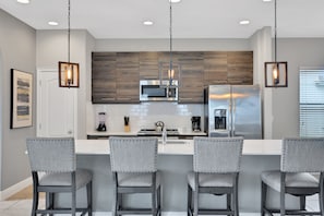 Eine moderne Küche mit Holzschränken, Edelstahlgeräten und Barhocker.