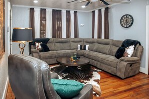 A living room with a sectional sofa, a leather armchair, a coffee table, and a patterned rug. - Big Spring 'Bison House' w/ Patio & Yard! (Big Spring)