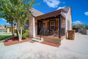A two-story house with a front porch, a staircase leading to the entrance, and a small garden area with mulch and a tree. - Big Spring 'Bison House' w/ Patio & Yard! (Big Spring)