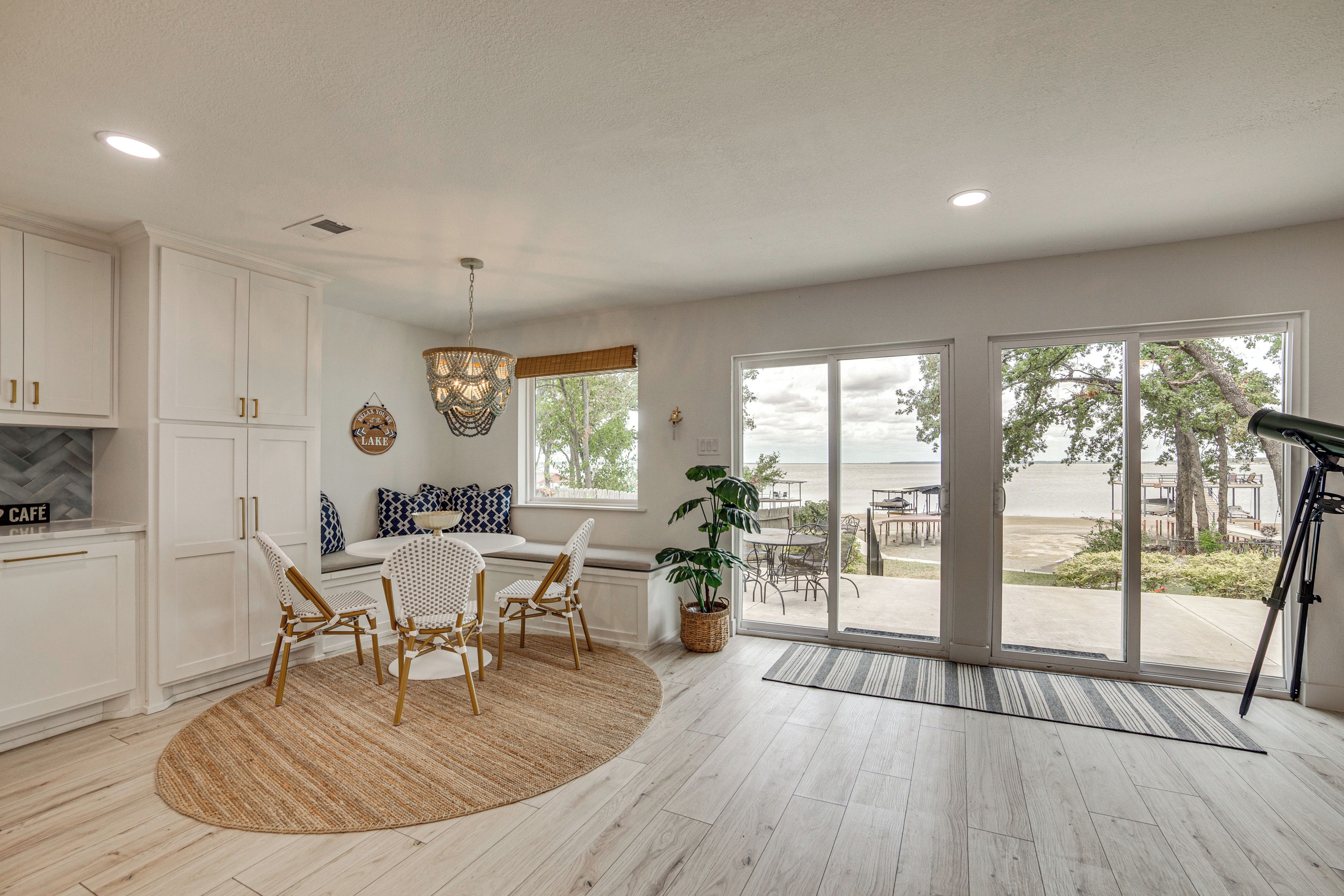 A spacious kitchen with white cabinetry, a dining area with a round table and chairs, and a large sliding glass door leading to an outdoor patio.