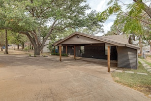 A single-story building with a covered garage area, a brick exterior, and a satellite dish on the roof. - Putt, Play & Splash! Cedar Creek Lake Getaway (Gun Barrel City)