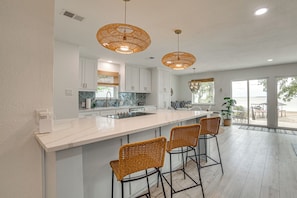 Una cocina moderna con una isla grande, taburetes de bar e iluminación colgante.