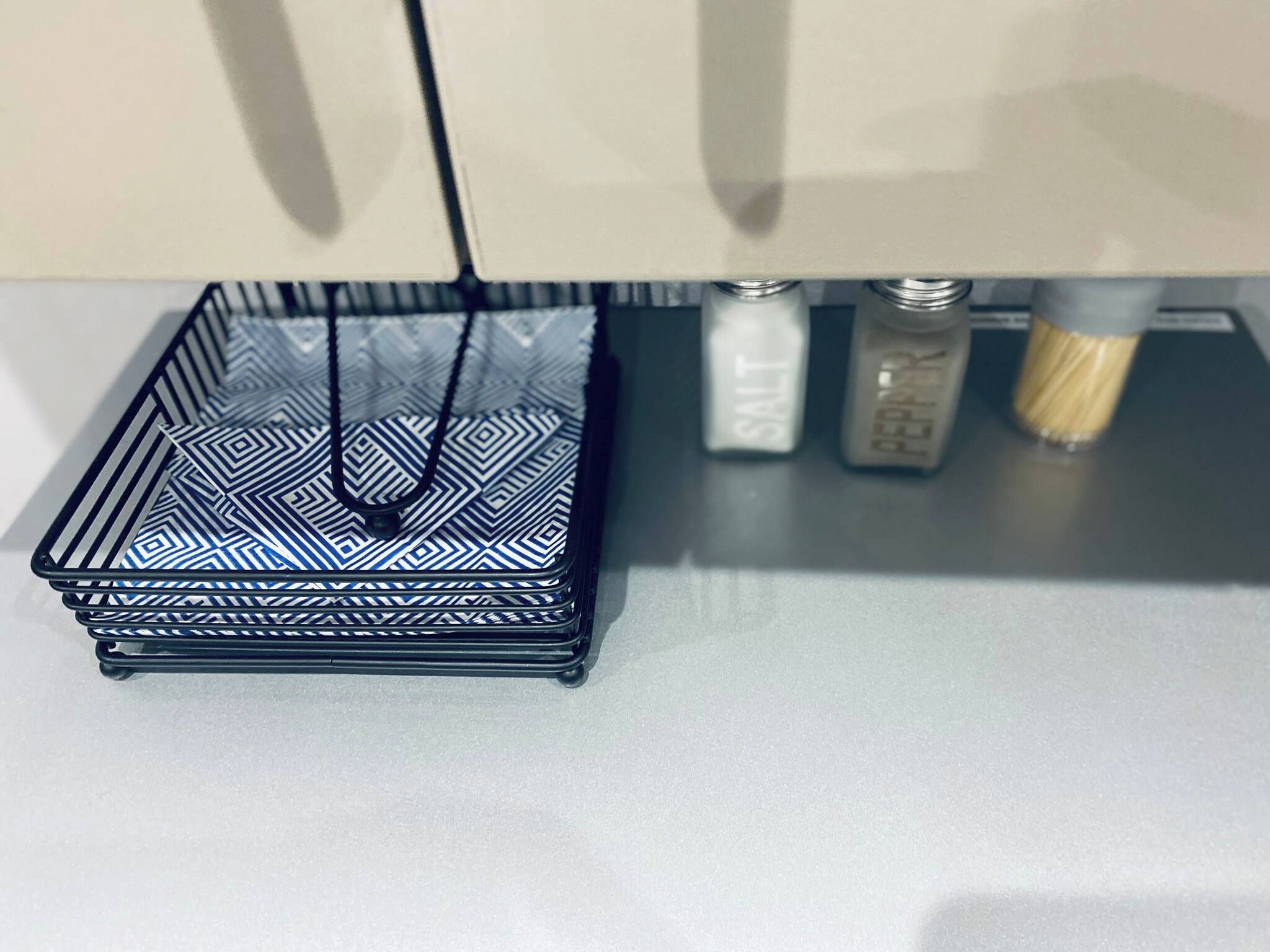 A black wire basket with a geometric pattern on a white surface.