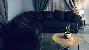 Een moderne woonkamer met een modulaire bank, een ronde salontafel met een plant en een wandklok.