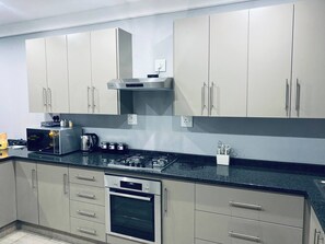 Una cocina moderna con electrodomésticos de acero inoxidable, armarios grises y encimera negra.