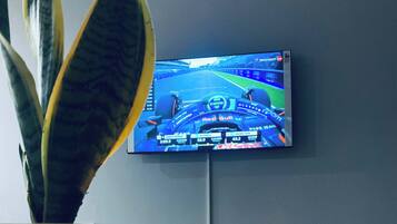 Een televisie waarop een racegame wordt afgespeeld, een potplant en een brandende kaars op een houten oppervlak.
