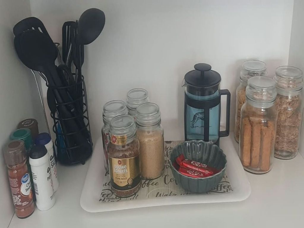 Un plan de travail de cuisine avec divers ustensiles de cuisine, une machine à café et des bocaux d’épices.