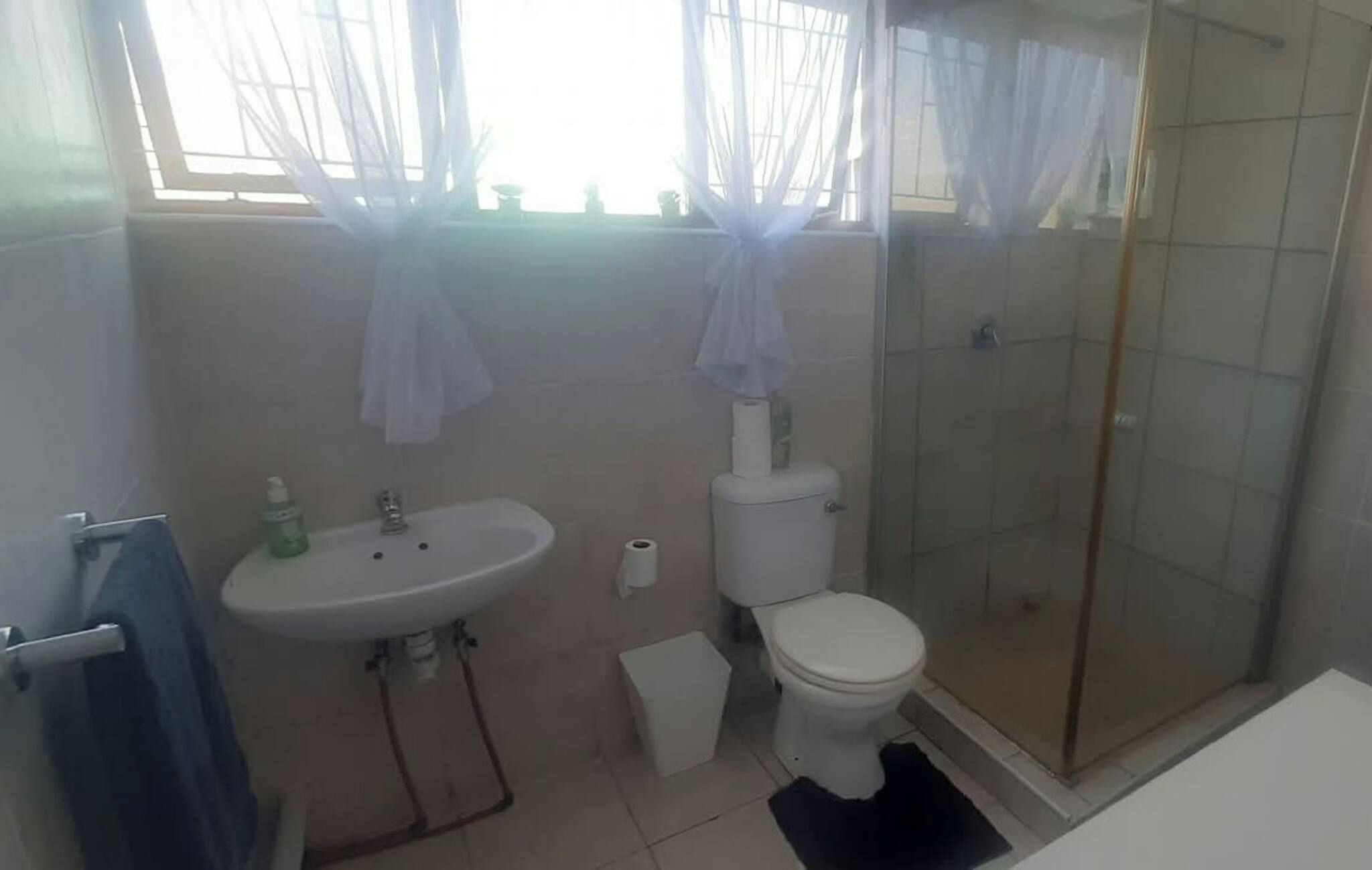 Un baño con lavamanos, inodoro y ducha con mampara de vidrio.