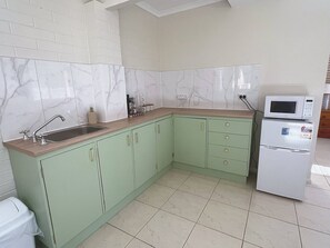 Eine kleine Küche mit Spüle, Schränken, einer Mikrowelle und einem Kühlschrank.