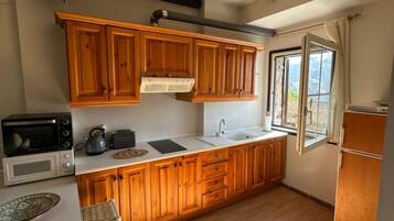 Cocina con gabinetes de madera, microondas, hervidor de agua, pileta y ventana con vistas.