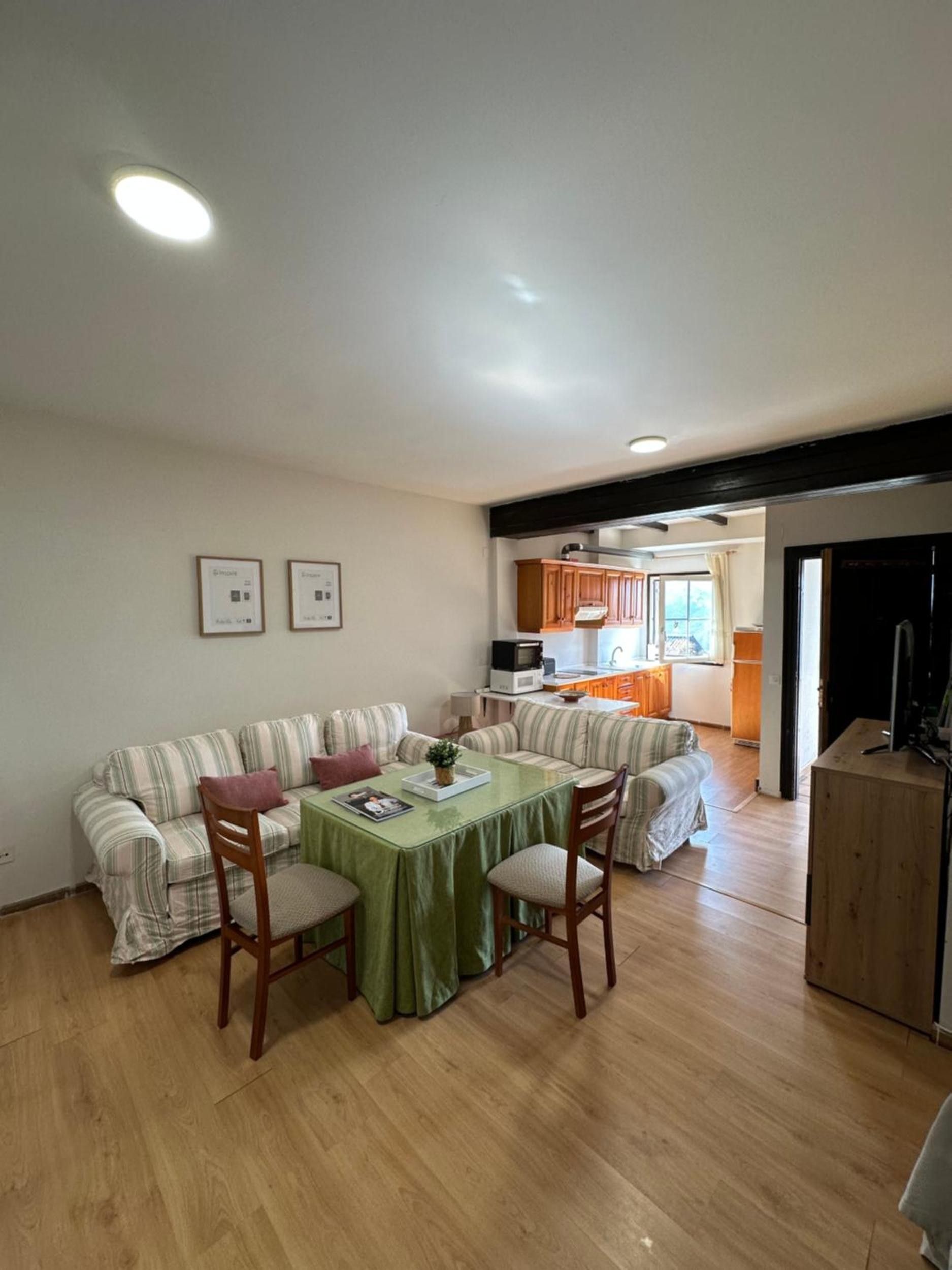 Een woonkamer met een zithoek, een eettafel met stoelen, en een keuken op de achtergrond.