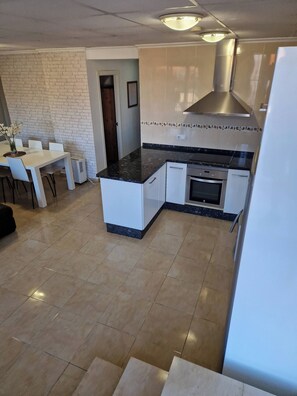 A modern kitchen with a central island, white cabinetry, and a built-in oven. - Tranquil Mountain Retreat with Private Pool in Quesa, Valencia (Quesa)