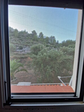A view through a window with a metal frame, looking out onto a terraced hillside with vegetation and a clear sky. - Tranquil Mountain Retreat with Private Pool in Quesa, Valencia (Quesa)
