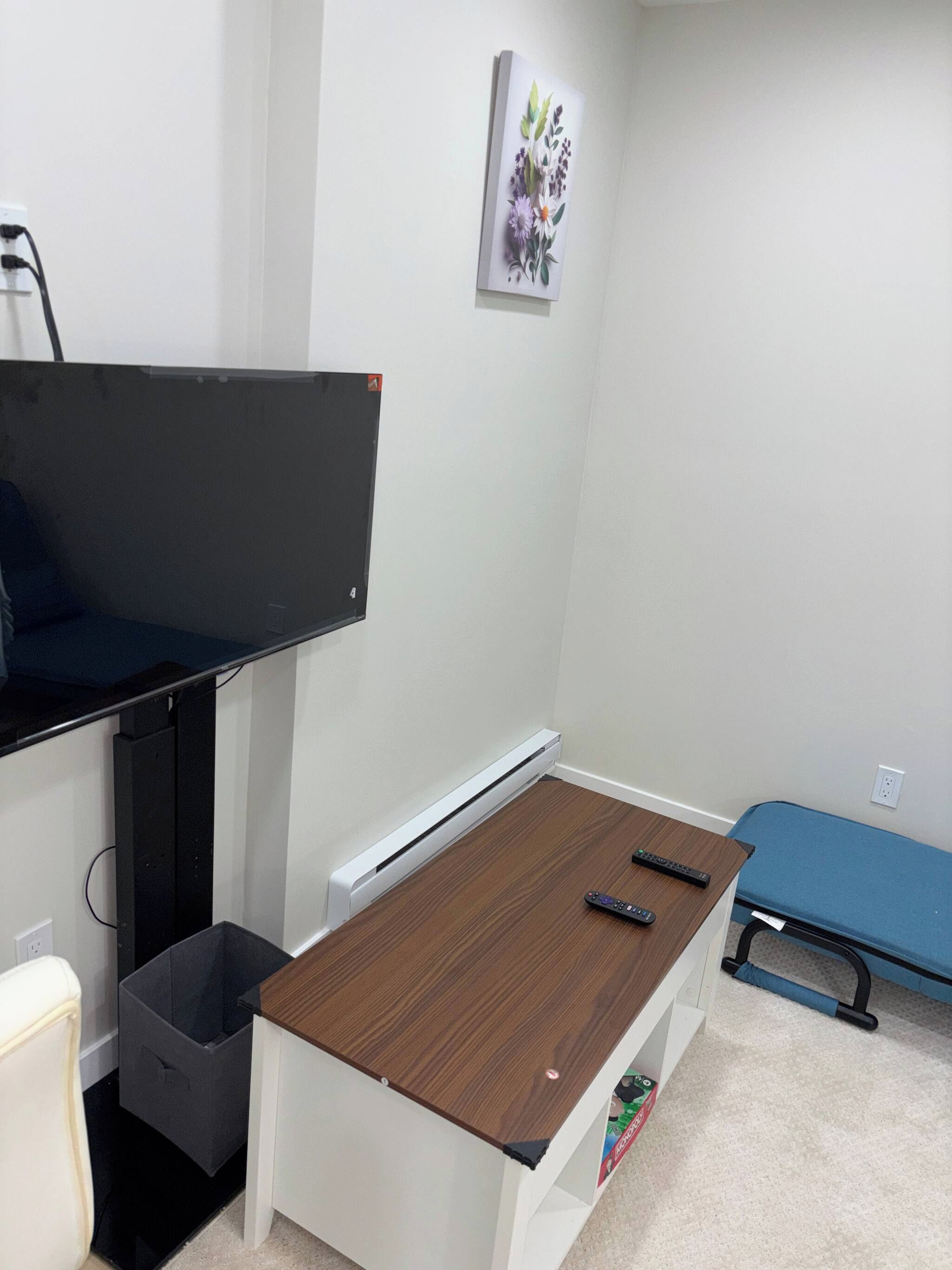 Une pièce comprenant un bureau, une chaise, un lit, un radiateur et un téléviseur fixé au mur.
