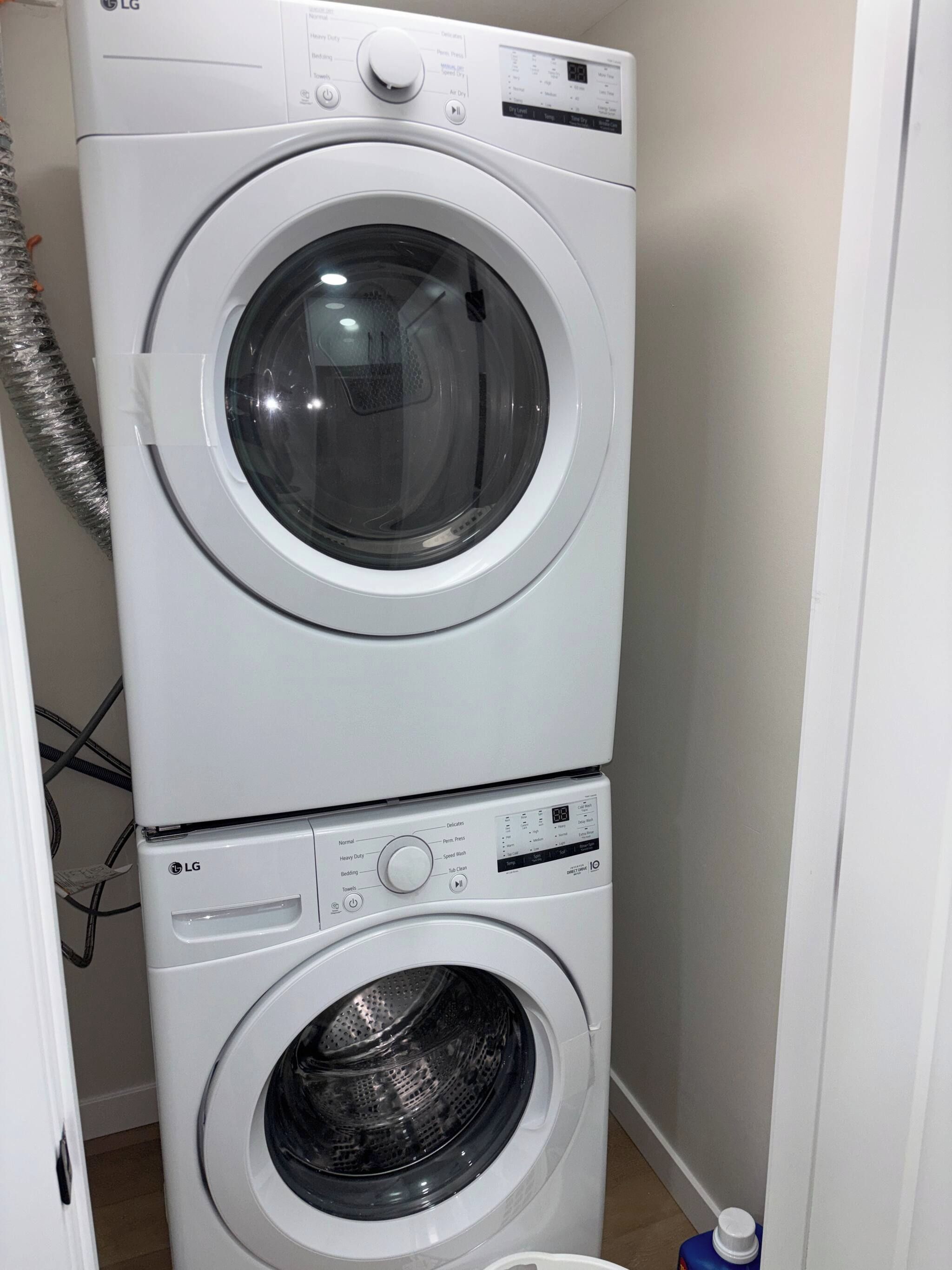 A stacked washer and dryer unit with control panels and a hose.