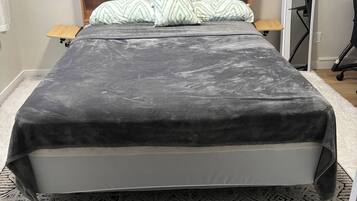 A bed with a headboard, a bedside table, and a patterned rug.