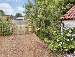 A garden with a gravel path, wooden fence, and flowering plants. - 2 bedroom accommodation in Fakenham (Fakenham)