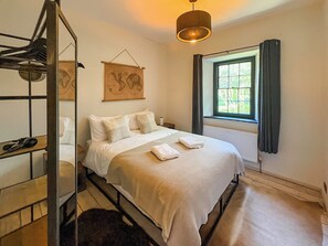 Een slaapkamer met een bed, een hanglamp, een raam met gordijnen en een kunstwerk aan de muur.