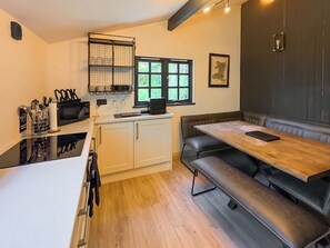 Cocina compacta con comedor, que incluye un ventanal, un estante en la pared y una banca.