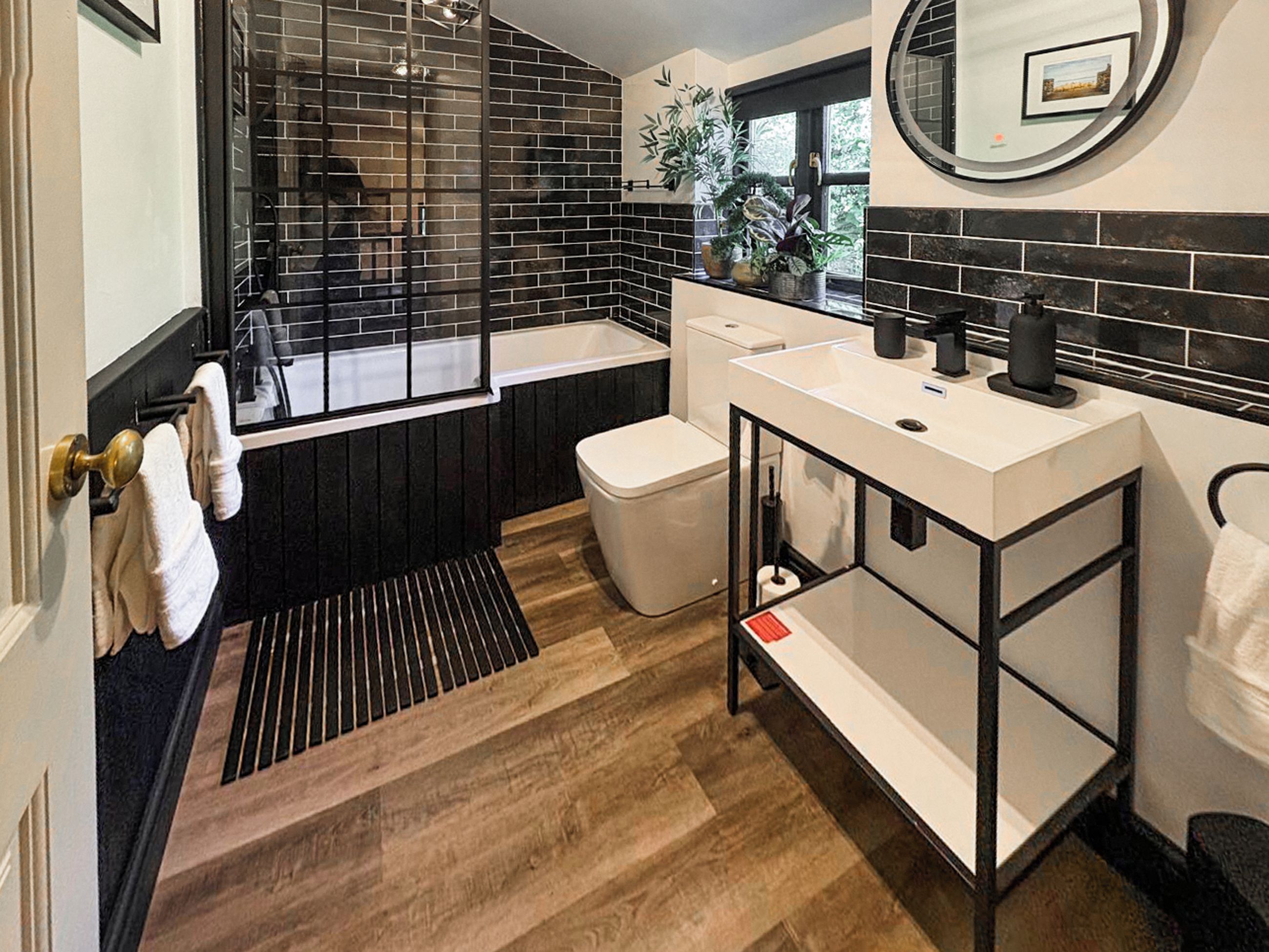 A modern bathroom with a black and white color scheme, a bathtub, a toilet, and a sink.