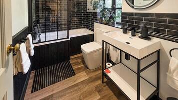 A modern bathroom with a black and white color scheme, a bathtub, a toilet, and a sink.