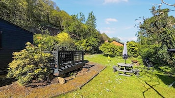 Ein Garten mit einer Holzbank, einem Picknicktisch und einem kleinen Schuppen.