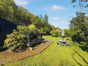 Ein Garten mit einer Holzbank, einem Picknicktisch und einem kleinen Schuppen.
