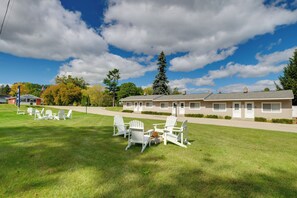 A motel with a grassy lawn, outdoor seating area, and a clear sky.