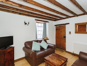 A living room with a brown leather sofa, a wooden coffee table, and a television on a wooden cabinet. - Barnaby's Lodge - UK51951 (Broadstairs)