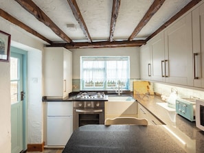 A kitchen with a window, white cabinets, a stove, and a refrigerator. - Barnaby's Lodge - UK51951 (Broadstairs)