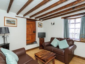 A furnished living room with a brown leather sofa, a wooden coffee table, a television, and a wooden door. - Barnaby's Lodge - UK51951 (Broadstairs)