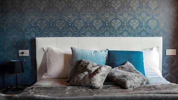 Ein Schlafzimmer mit strukturierter Tapete, einem weißen Kopfteil und einem Bett mit vielen Kissen.